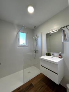 une salle de bain blanche avec lavabo et douche dans l'établissement Chez Mimi - Bellevue, à Raulhac