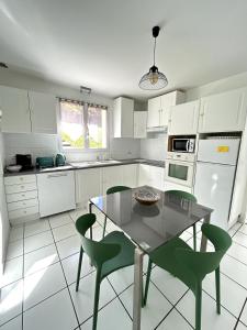 une cuisine avec des armoires blanches et une table et des chaises dans l'établissement Chez Mimi - Bellevue, à Raulhac 2 autres photos