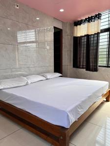a bedroom with a large bed with white sheets at Shanti Nivas Homestay in Māvalli
