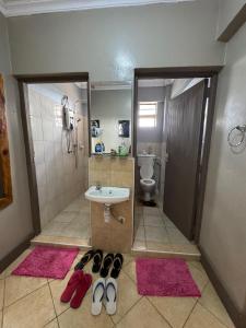 a bathroom with a sink and a toilet and two pairs of shoes at Lovely 2-bedroom Fully-Furnished apartment in Nanyuki