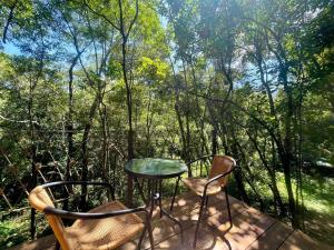 a table and chairs on a deck with trees at chalé borboletário in Brumadinho +2 photos