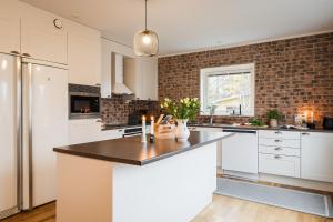 a kitchen with white cabinets and a brick wall at Guestly Homes - Spacious 2BR Executive Residence in Luleå