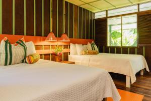 a hotel room with two beds and a window at Mawamba Lodge in Tortuguero +65 photos