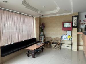 une salle d'attente avec un canapé noir et des chaises dans l'établissement Dancenter Hotel Oriental, à Kota Kinabalu