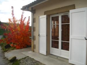 a house with white doors and a red tree at Gîte La Combe Verte in Ratières