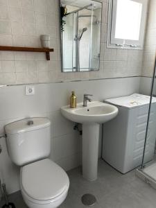 a white bathroom with a toilet and a sink at Atico playa de Rota in Rota