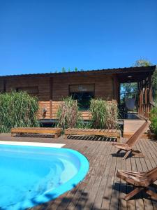 a swimming pool with two chairs and a house at Cabaña en la Colina in Sierra de los Padres