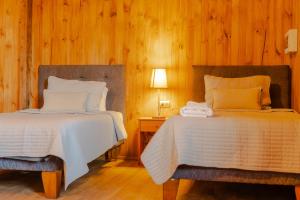 two beds in a room with wood paneled walls at Cabañas Teno Sandwich in Teno +7 photos