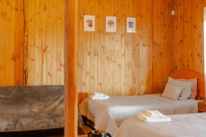 two beds in a room with wooden walls at Cabañas Teno Sandwich in Teno