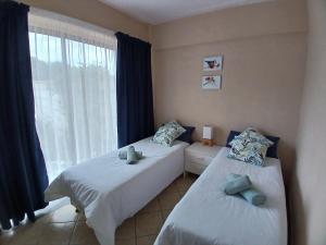 two beds in a room with a window at Kaaimans Crest Sea-View Apartments - Great Brak River in Groot Brak Rivier