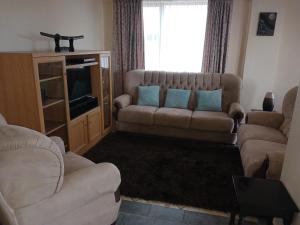 a living room with a couch and a television at Kaaimans Crest Sea-View Apartments - Great Brak River in Groot Brak Rivier