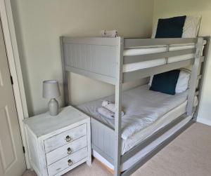 ein weißes Etagenbett in einem Zimmer mit einem Nachttisch in der Unterkunft 'Shakespeare Cottage' - Free Parking near Salisbury Railway Station & Walk to City in Salisbury