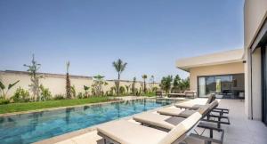 ein Swimmingpool mit Liegestühlen und ein Haus in der Unterkunft Villa Gaspard - Piscine et jardin Privée Sans vis-à-vis Wifi HD in Oulad Akkou