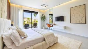 ein weißes Schlafzimmer mit einem großen Bett und einem TV in der Unterkunft Villa Gaspard - Piscine et jardin Privée Sans vis-à-vis Wifi HD in Oulad Akkou