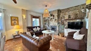a living room with leather furniture and a stone wall at Villa Malaga con Jacuzzi Piscina vallada Barbacoa By AndaraHolidays in Sayalonga