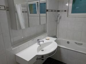 a white bathroom with a sink and a bath tub at Familienzimmer Bremgarten in Bremgarten