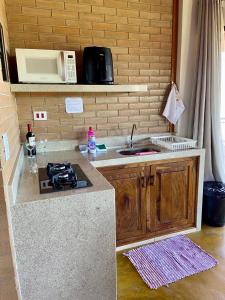 a kitchen with a counter with a stove and a sink at Chalés Terras Altas in Gonçalves +76 photos
