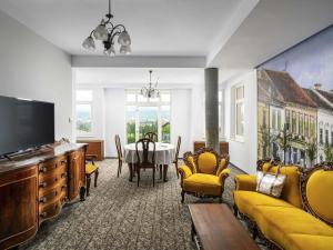a living room with a table and yellow furniture at Mercure Medias Binderbubi Hotel And Spa in Mediaş