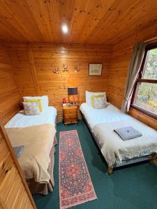 a bedroom with two beds in a log cabin at Braemar Lodge Cabins Not for profit in Braemar