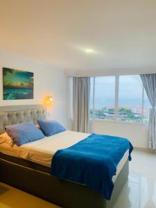 a bedroom with a bed with blue sheets and a large window at apartamento 1302 in Cartagena de Indias