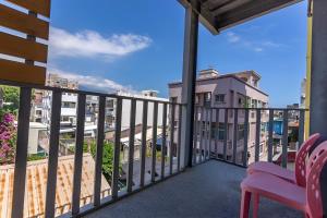 Un balcón con una silla rosa y vistas. en White Sand Homestay, en Hualien City