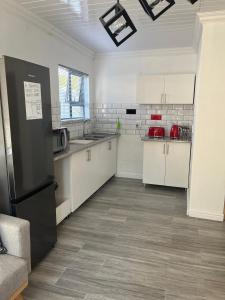 a kitchen with white cabinets and a black refrigerator at Balmoral Kids Party Venue in Cape Town