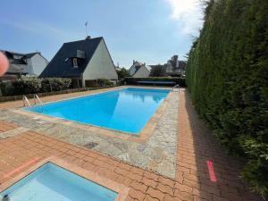 una gran piscina con un camino de ladrillo alrededor en appartement bord de mer, en Benerville-sur-Mer