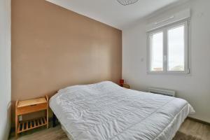 ein Schlafzimmer mit einem weißen Bett und einem Fenster in der Unterkunft La Guérinière - 650m de la plage - Jardin in La Guérinière