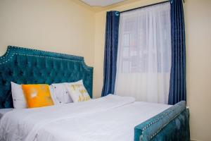 Bett mit blauem Kopfteil und Fenster in der Unterkunft Danross Nest in Gatunga