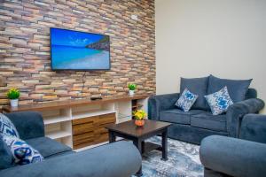 ein Wohnzimmer mit 2 Sofas und einem TV an einer Backsteinwand in der Unterkunft Danross Nest in Gatunga