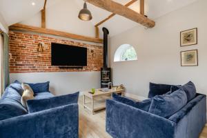 un salon avec des canapés bleus et un mur de briques dans l'établissement Iken Barn, à Neatishead