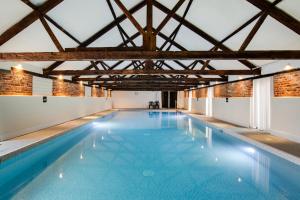 une grande piscine avec de l'eau bleue dans un immeuble dans l'établissement Iken Barn, à Neatishead