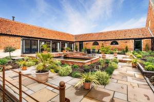une cour avec des plantes en pot et un bâtiment en briques dans l'établissement Iken Barn, à Neatishead