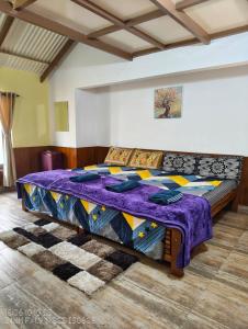 a bedroom with a large bed with a purple blanket at Pleasant Stay Coonoor-A Serene Hillside Retreat in Coonoor