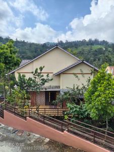 a house with a fence in front of it at Pleasant Stay Coonoor-A Serene Hillside Retreat in Coonoor
