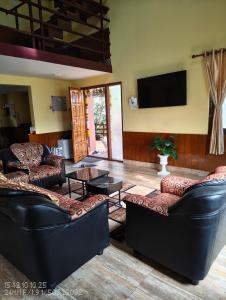 a living room with couches and a flat screen tv at Pleasant Stay Coonoor-A Serene Hillside Retreat in Coonoor