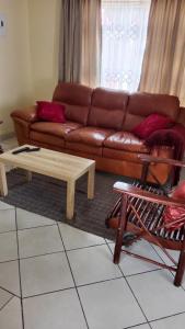 ein Wohnzimmer mit einem braunen Sofa und einem Couchtisch in der Unterkunft NEMARA Self Catering Lodge in Polokwane