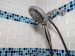 a shower head in a bathroom with blue and white tiles at Highland Apartment in Columbus +25 photos