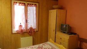 1 dormitorio con 1 cama, TV y ventana en Albergo Ristorante K2, en Roana