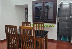 duas cadeiras de madeira e uma mesa num quarto em The Signature Suites em Edappally