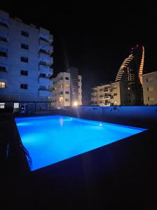 a large blue swimming pool at night with buildings at Beachfront Amazing New Apartment in Limassol +7 photos