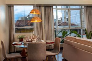 een eetkamer met een tafel en een groot raam bij Nuna Atelier in Cuzco