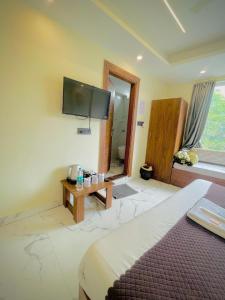 a bedroom with a bed and a tv on the wall at Hotel Mount View Inn with terrace Ganga view in Rishīkesh