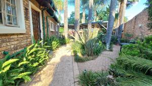 a garden with palm trees and plants next to a building at Granny at Umgeni in Pretoria