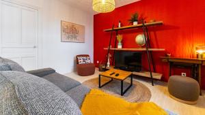 a living room with a gray couch and a red wall at L'orée du Parc in Longvic
