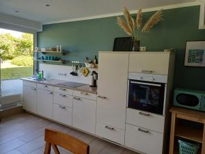 a kitchen with white cabinets and a green wall at Ferienwohnung am Schöhsee in Plön