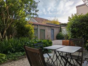 a patio with a table and chairs in a garden at L'orée du Parc in Longvic
