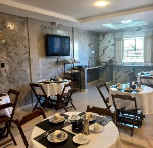 a dining room with tables and chairs and a television at Pousada GPC in Macaé