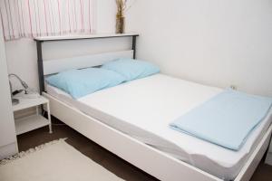 Dormitorio pequeño con cama blanca y almohadas azules en Apartments "I & I", en Pag