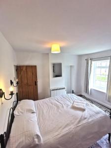 a white bed in a bedroom with a window at Church view Cottage in Osmotherley